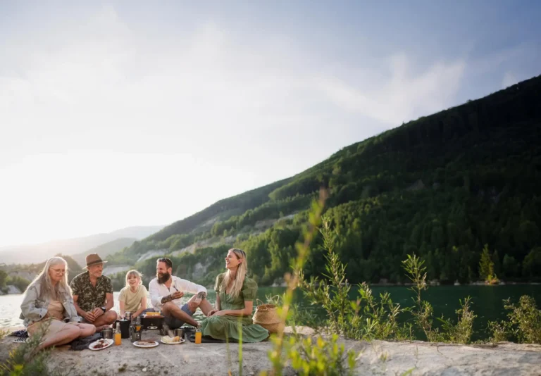 family sitting next to lake having a picnic